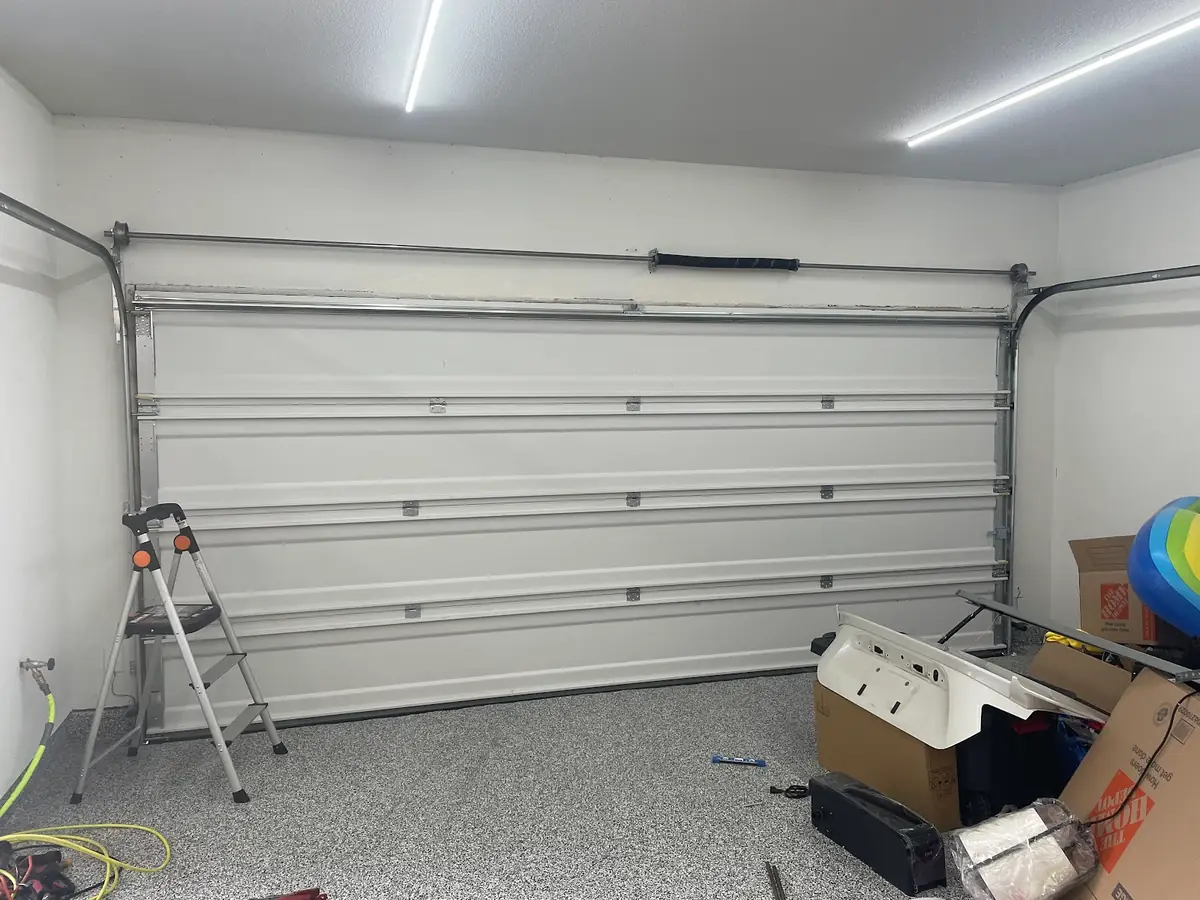 Torsion spring and shaft above a white sectional garage door